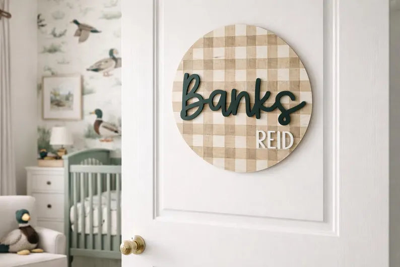 Round decorative sign with 'Banks Reid' on a white door in a nursery in a Duck themed Nursery.